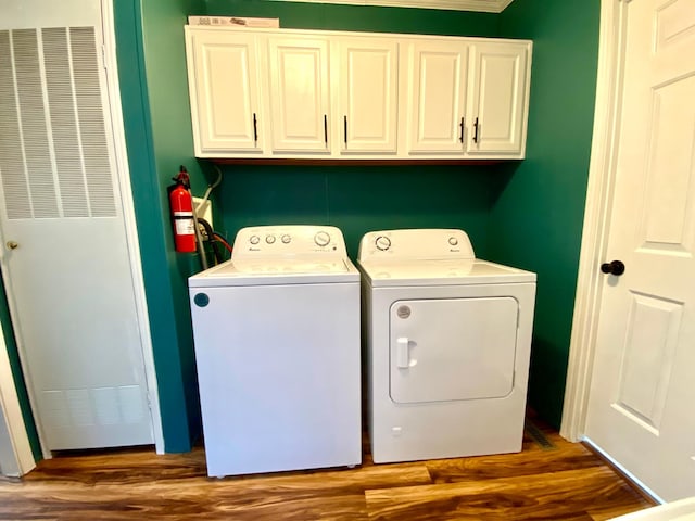 clothes washing area with cabinets, dark hardwood / wood-style floors, and washing machine and dryer