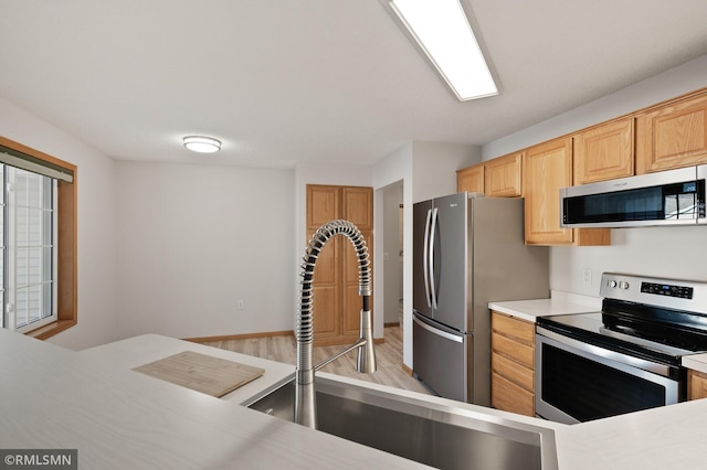 kitchen with sink, light hardwood / wood-style flooring, stainless steel appliances, and light brown cabinets