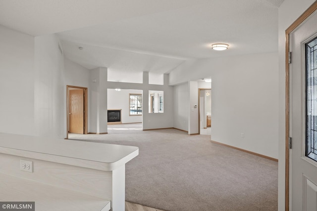 unfurnished living room with lofted ceiling and light carpet