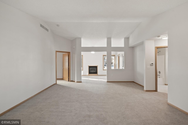 unfurnished living room featuring high vaulted ceiling and light carpet