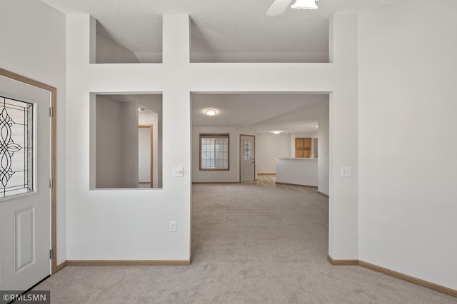 carpeted entryway featuring ceiling fan, a towering ceiling, and a textured ceiling