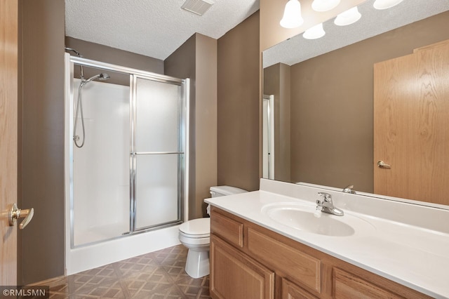 bathroom with an enclosed shower, vanity, toilet, and a textured ceiling