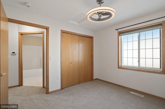 unfurnished bedroom featuring light colored carpet, a closet, and a textured ceiling