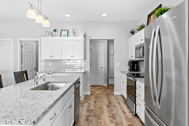 kitchen with decorative light fixtures, white cabinetry, an island with sink, sink, and stainless steel appliances