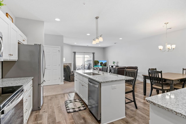 kitchen with hanging light fixtures, white cabinetry, appliances with stainless steel finishes, and a center island with sink