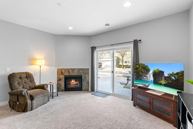 sitting room featuring a tile fireplace, light carpet, and a textured ceiling