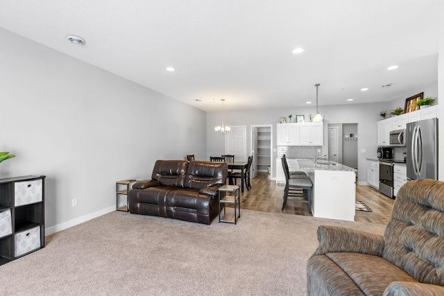 living room featuring light colored carpet, a chandelier, and sink