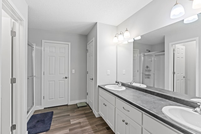 bathroom featuring an enclosed shower, vanity, wood-type flooring, and a textured ceiling