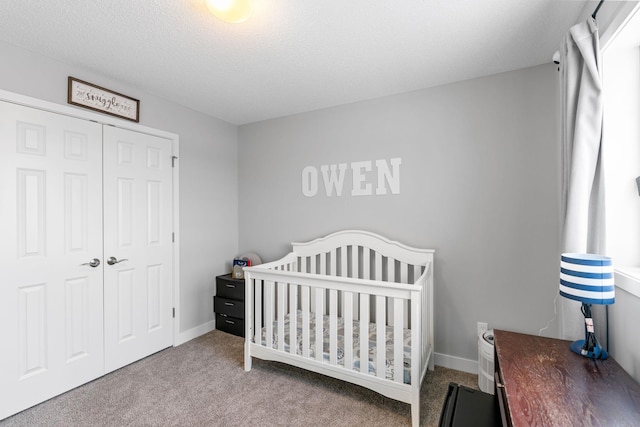 bedroom with a nursery area, light carpet, a textured ceiling, and a closet