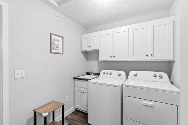 laundry room with sink, dark hardwood / wood-style floors, cabinets, washer and dryer, and a textured ceiling