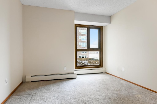 carpeted empty room with baseboard heating and a textured ceiling