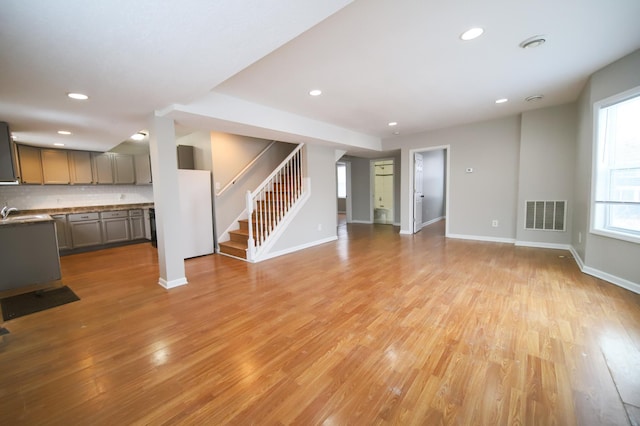 unfurnished living room featuring sink and light hardwood / wood-style flooring