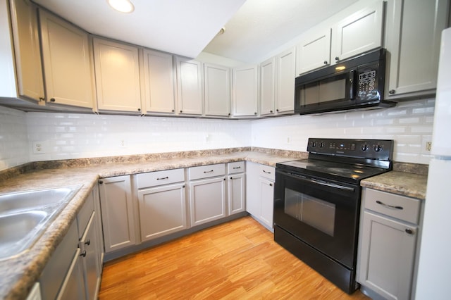 kitchen with sink, gray cabinets, black appliances, and light hardwood / wood-style floors