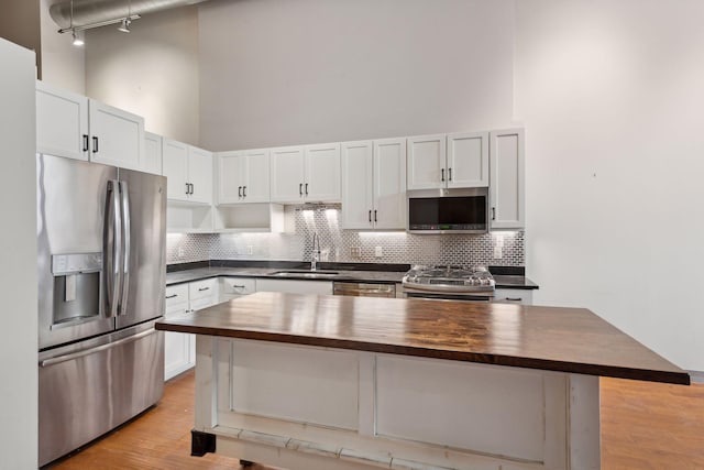 kitchen with sink, white cabinets, wooden counters, a center island, and stainless steel appliances