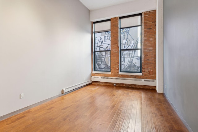 unfurnished room with a baseboard heating unit and hardwood / wood-style floors