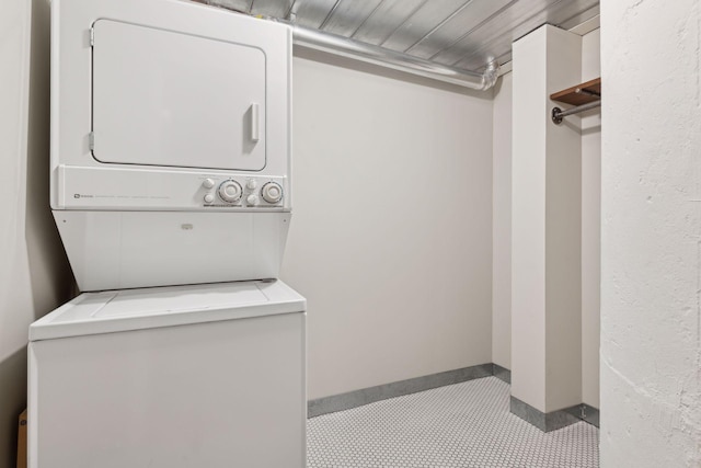 clothes washing area featuring wooden ceiling and stacked washer and clothes dryer