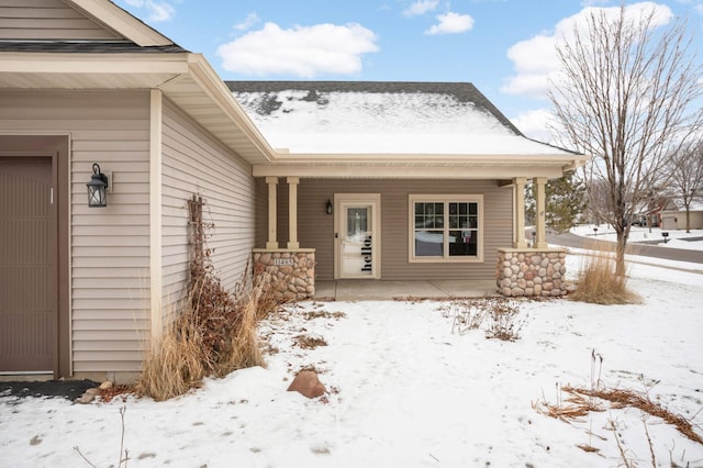 snow covered property entrance with a porch