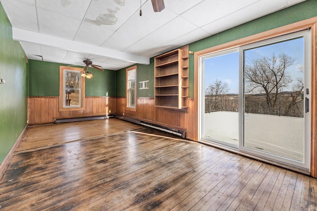 spare room featuring dark wood-type flooring, ceiling fan, beam ceiling, and baseboard heating