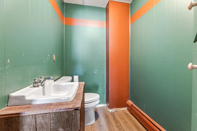 bathroom featuring a baseboard radiator, hardwood / wood-style floors, vanity, and toilet