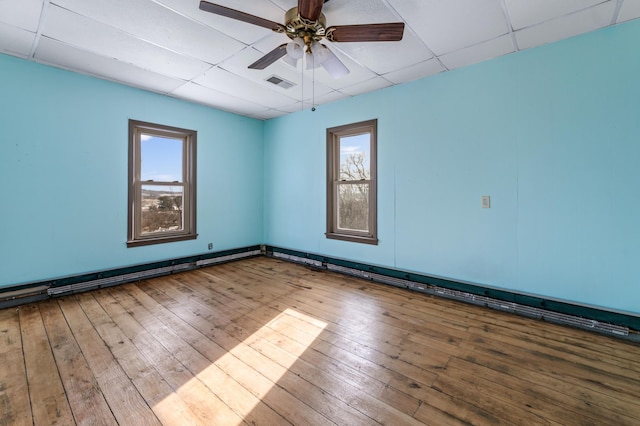 spare room featuring wood-type flooring, a drop ceiling, and ceiling fan