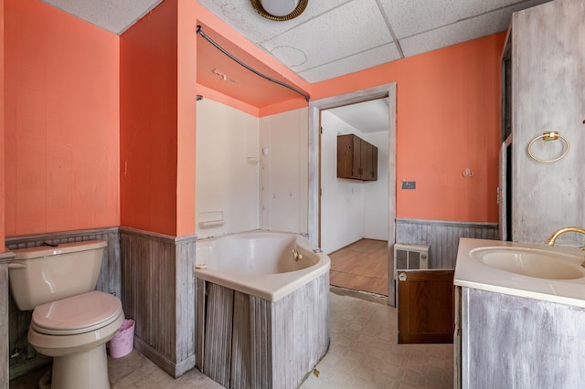 bathroom with vanity, a drop ceiling, a bathtub, and toilet