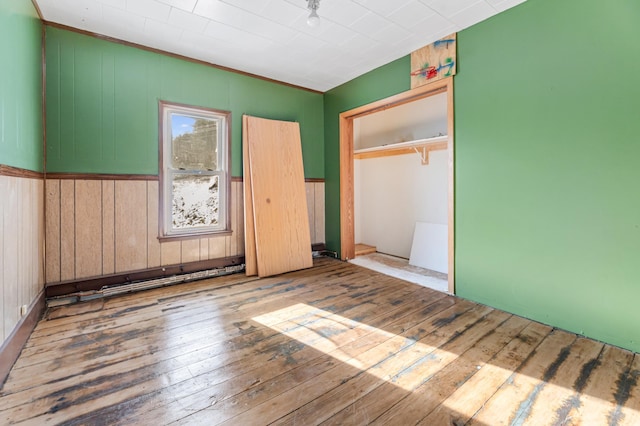 unfurnished bedroom featuring wood walls, light wood-type flooring, and a closet