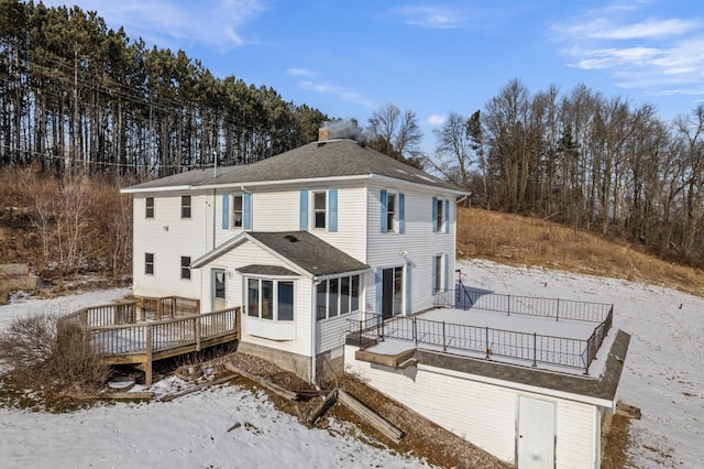 snow covered back of property with a wooden deck