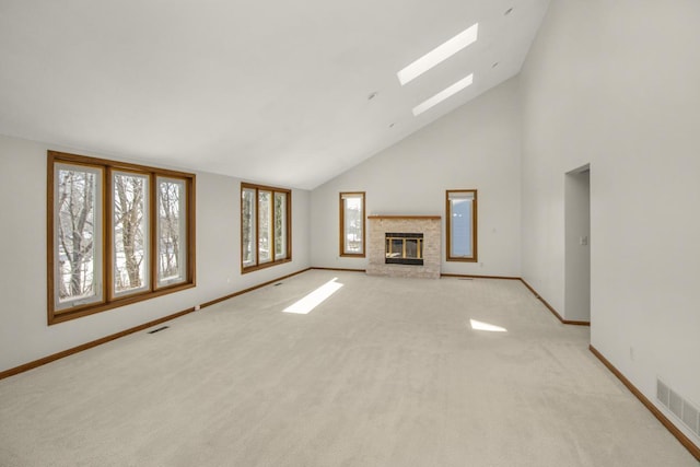 unfurnished living room featuring a skylight, high vaulted ceiling, a brick fireplace, and light carpet