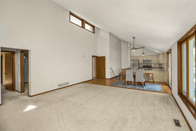 unfurnished dining area with sink, a healthy amount of sunlight, light carpet, and ceiling fan