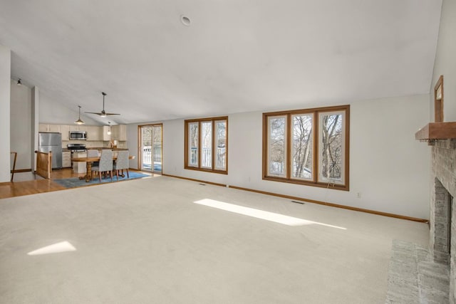 unfurnished living room with lofted ceiling, light carpet, and a brick fireplace