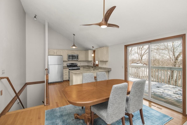 dining area featuring sink, vaulted ceiling, ceiling fan, and light wood-type flooring