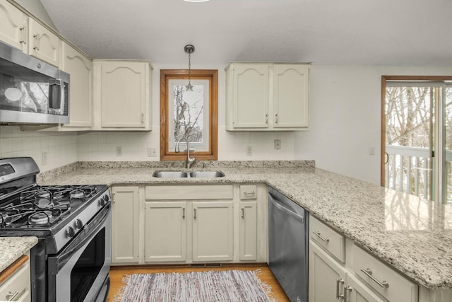 kitchen featuring hanging light fixtures, sink, backsplash, light stone counters, and stainless steel appliances