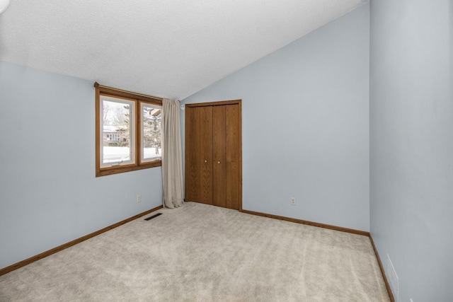 carpeted spare room with vaulted ceiling