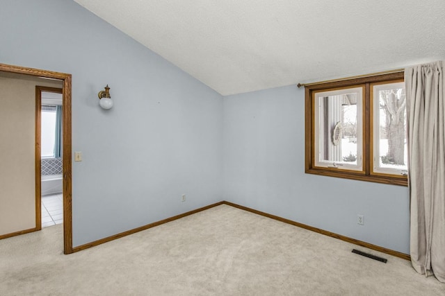 spare room featuring light carpet and lofted ceiling