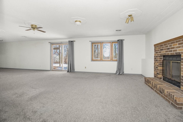 unfurnished living room with a brick fireplace, a textured ceiling, carpet floors, and ceiling fan