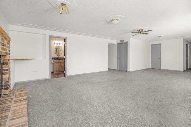 unfurnished living room featuring crown molding, a fireplace, a textured ceiling, carpet floors, and ceiling fan