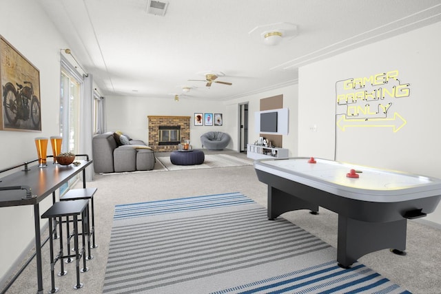 playroom featuring a fireplace, carpet flooring, ceiling fan, and ornamental molding