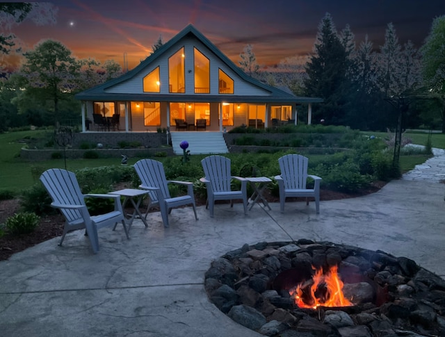 back house at dusk featuring a patio and a fire pit