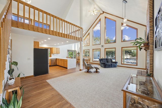 living room featuring ceiling fan, a towering ceiling, and light hardwood / wood-style floors