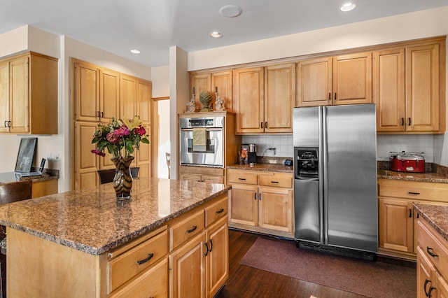 kitchen with stone countertops, appliances with stainless steel finishes, dark wood-type flooring, tasteful backsplash, and a center island