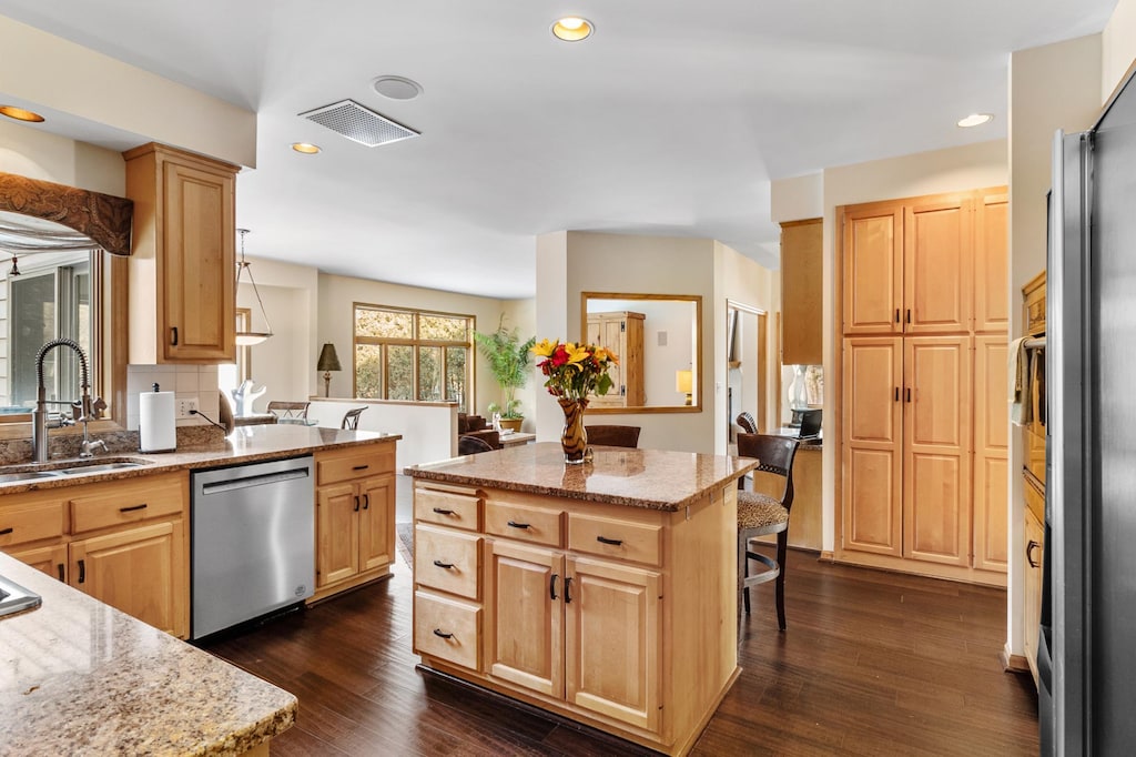 kitchen featuring sink, stainless steel appliances, a kitchen island, and light brown cabinets