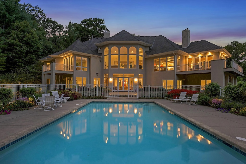 back house at dusk with a fenced in pool and a patio area