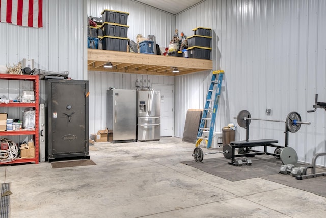 garage with wooden walls and stainless steel refrigerator with ice dispenser