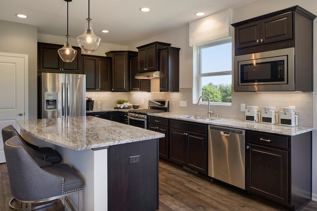 kitchen featuring appliances with stainless steel finishes, a kitchen island, dark hardwood / wood-style flooring, sink, and hanging light fixtures