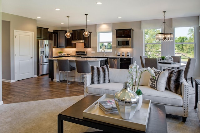 living room with sink, dark wood-type flooring, and an inviting chandelier