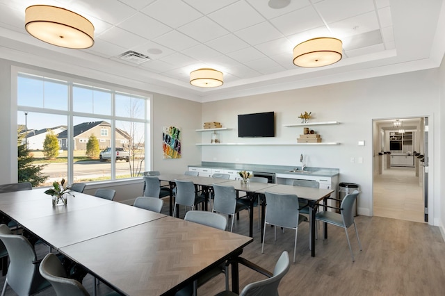 dining area featuring sink, a raised ceiling, and hardwood / wood-style floors