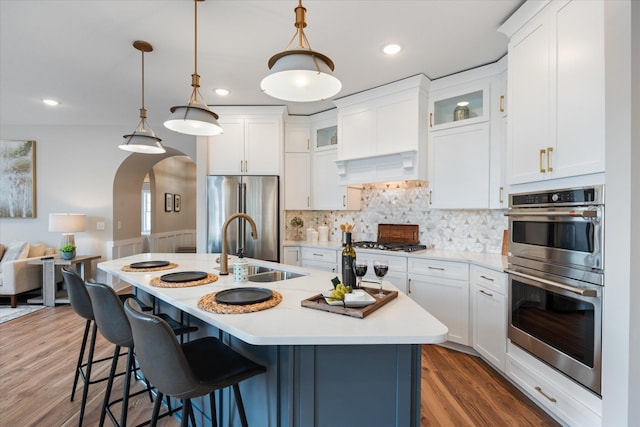 kitchen with decorative light fixtures, an island with sink, sink, and stainless steel appliances