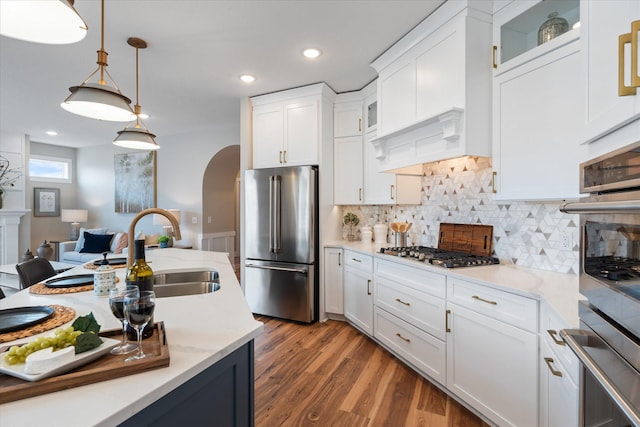 kitchen with hanging light fixtures, appliances with stainless steel finishes, sink, white cabinets, and tasteful backsplash