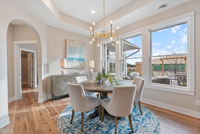 dining room featuring light hardwood / wood-style flooring, a notable chandelier, and a tray ceiling