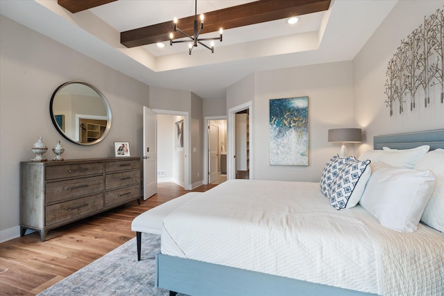 bedroom featuring wood-type flooring, an inviting chandelier, and a tray ceiling